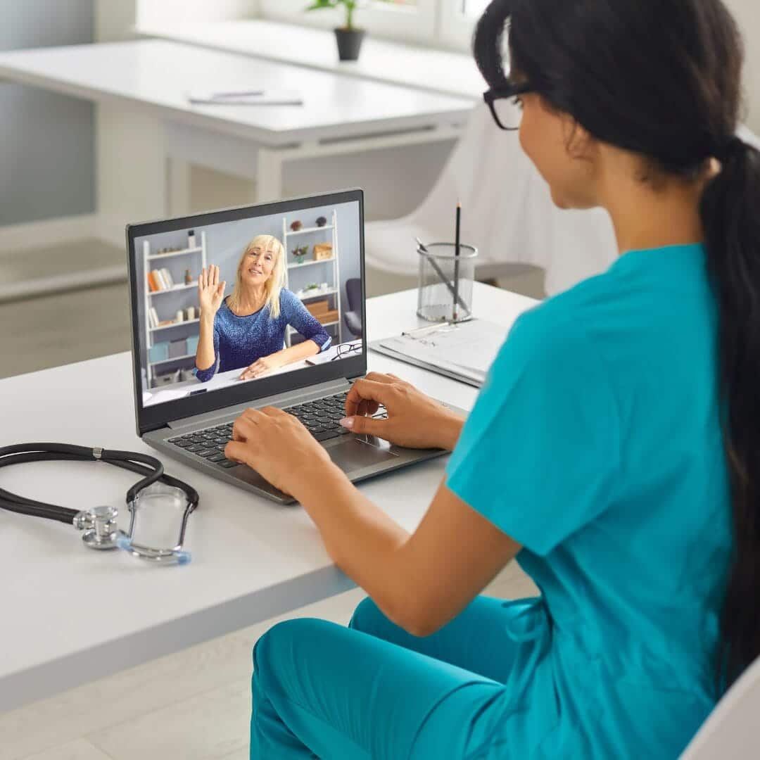 Infirmière en tenue médicale suivant une formation continue en classe virtuelle sur son ordinateur portable